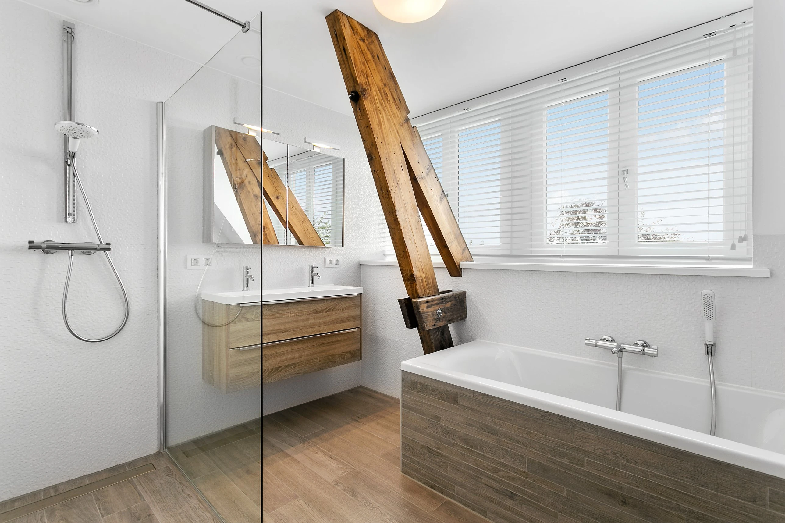 Badkamer met een inloopdouche, een houten dubbele wastafel en een oude houten dakbalk die door de ruimte loopt