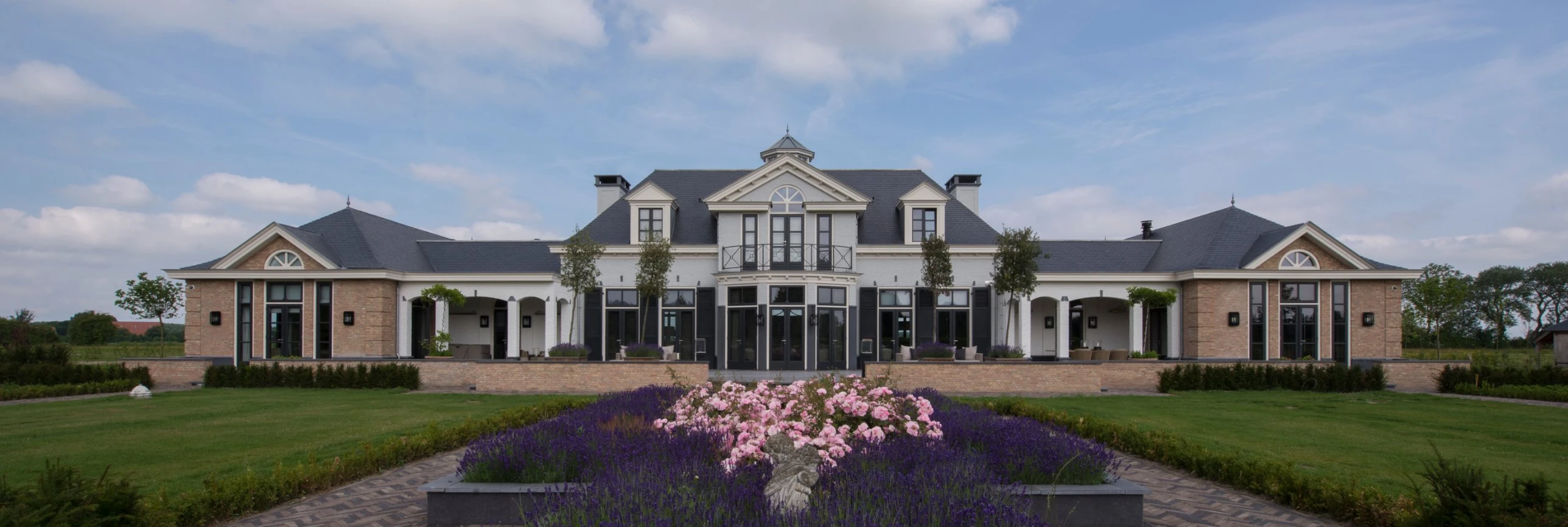 Tuinzijde van een villa in Sommelsdijk met lavendel en rozen in het hart van een symmetrische tuin