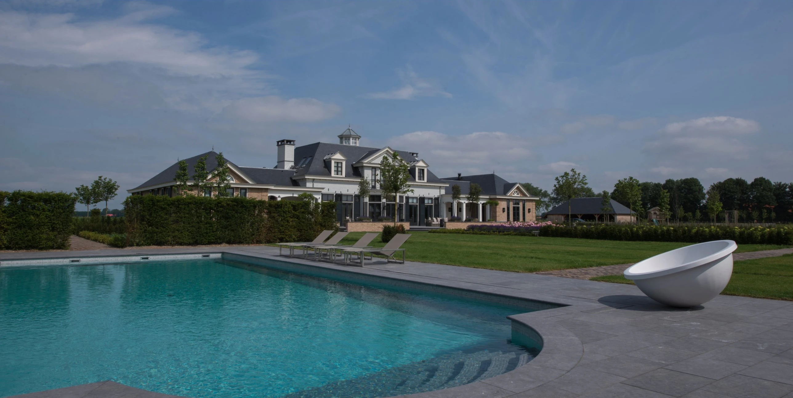 Zwembad met een leistenen rand en de villa in Sommelsdijk op de achtergrond