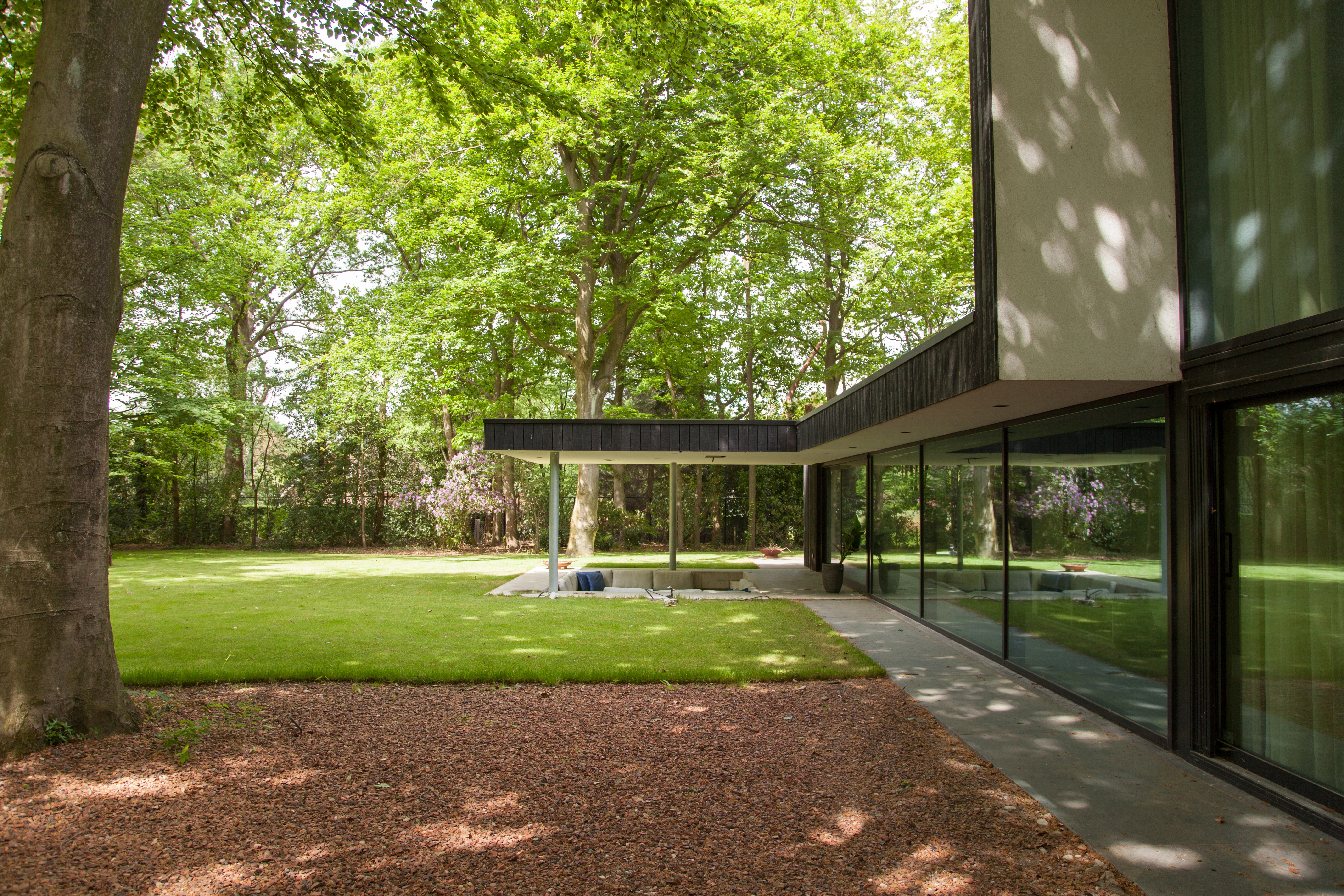 Zijaanzicht van de overkapping langs de glazen pui van de villa