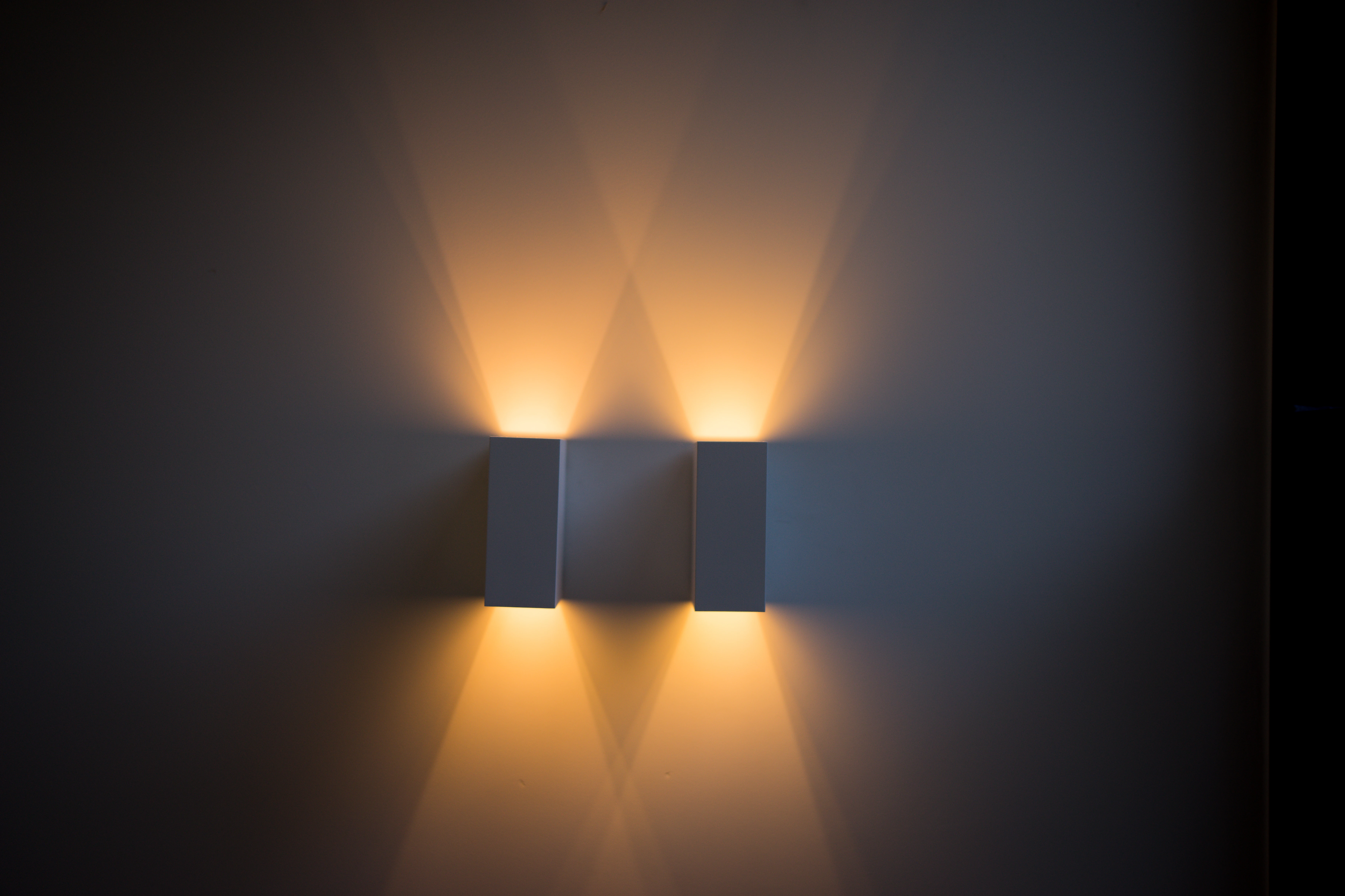 Twee wandarmaturen die licht omhoog en omlaag werpen op een rustige wand