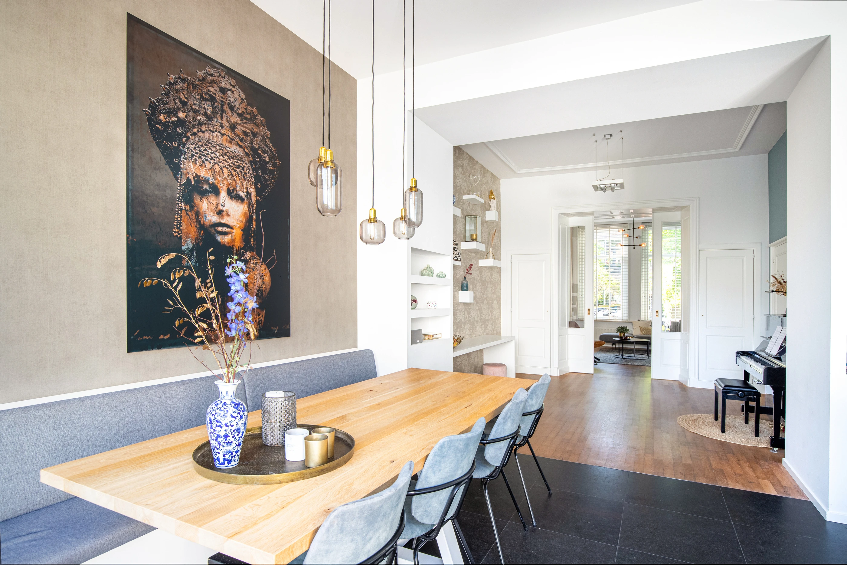 Eetkamer met houten tafel en doorkijk naar de keuken