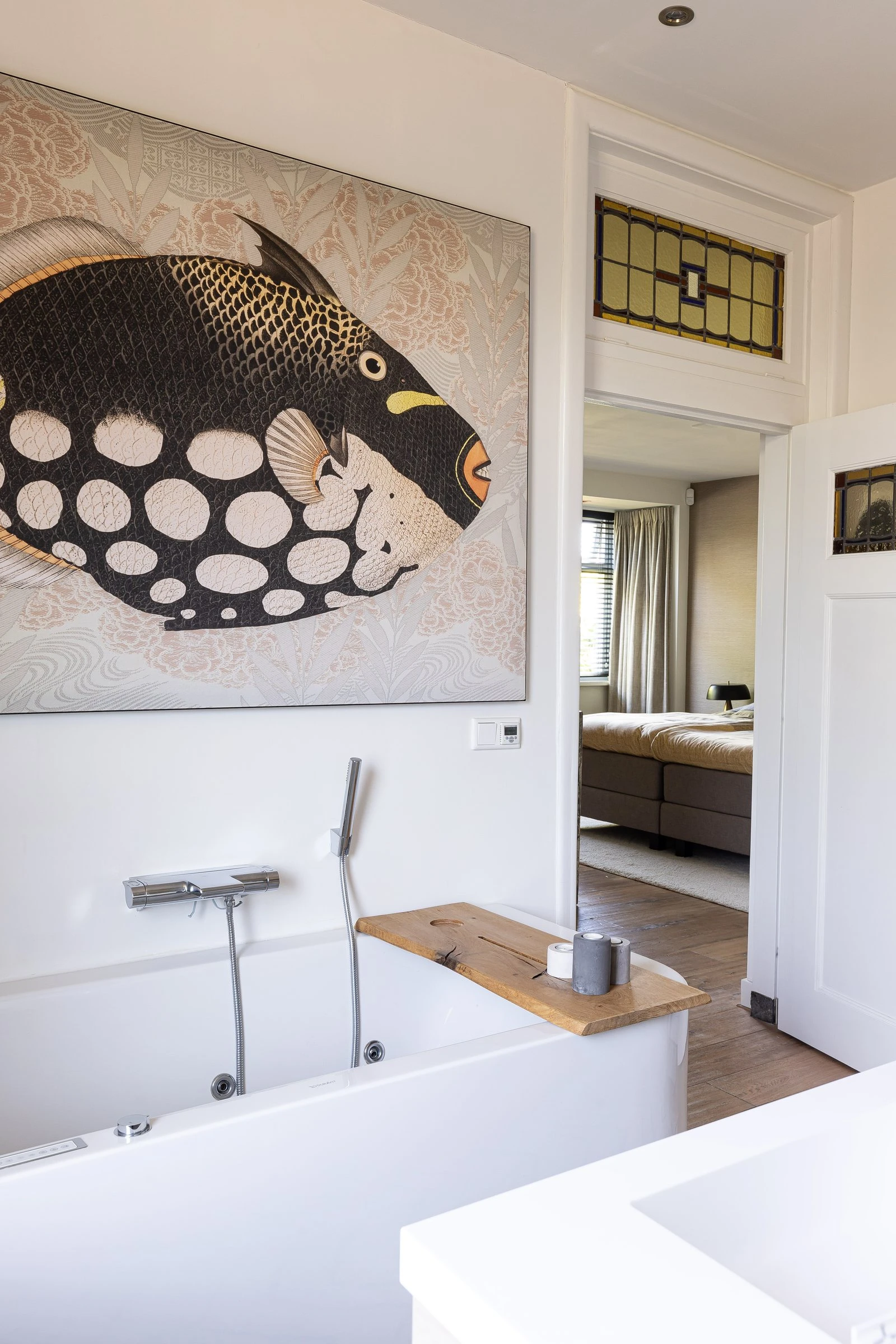 Badkamer met kunstwerk van een vis, met doorkijk naar de slaapkamer