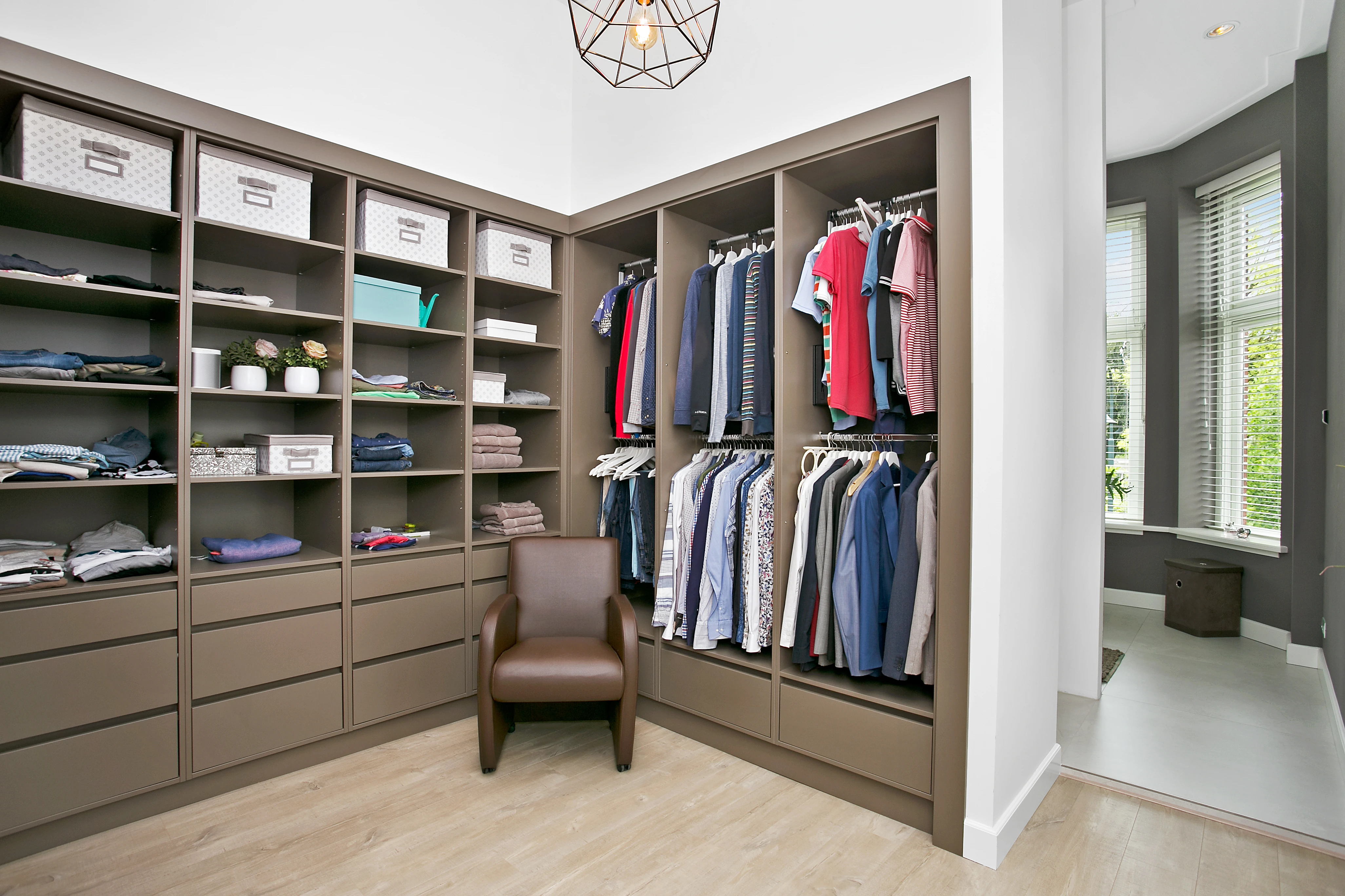 Inloopkast met kledingkasten in taupe en een leren fauteuil