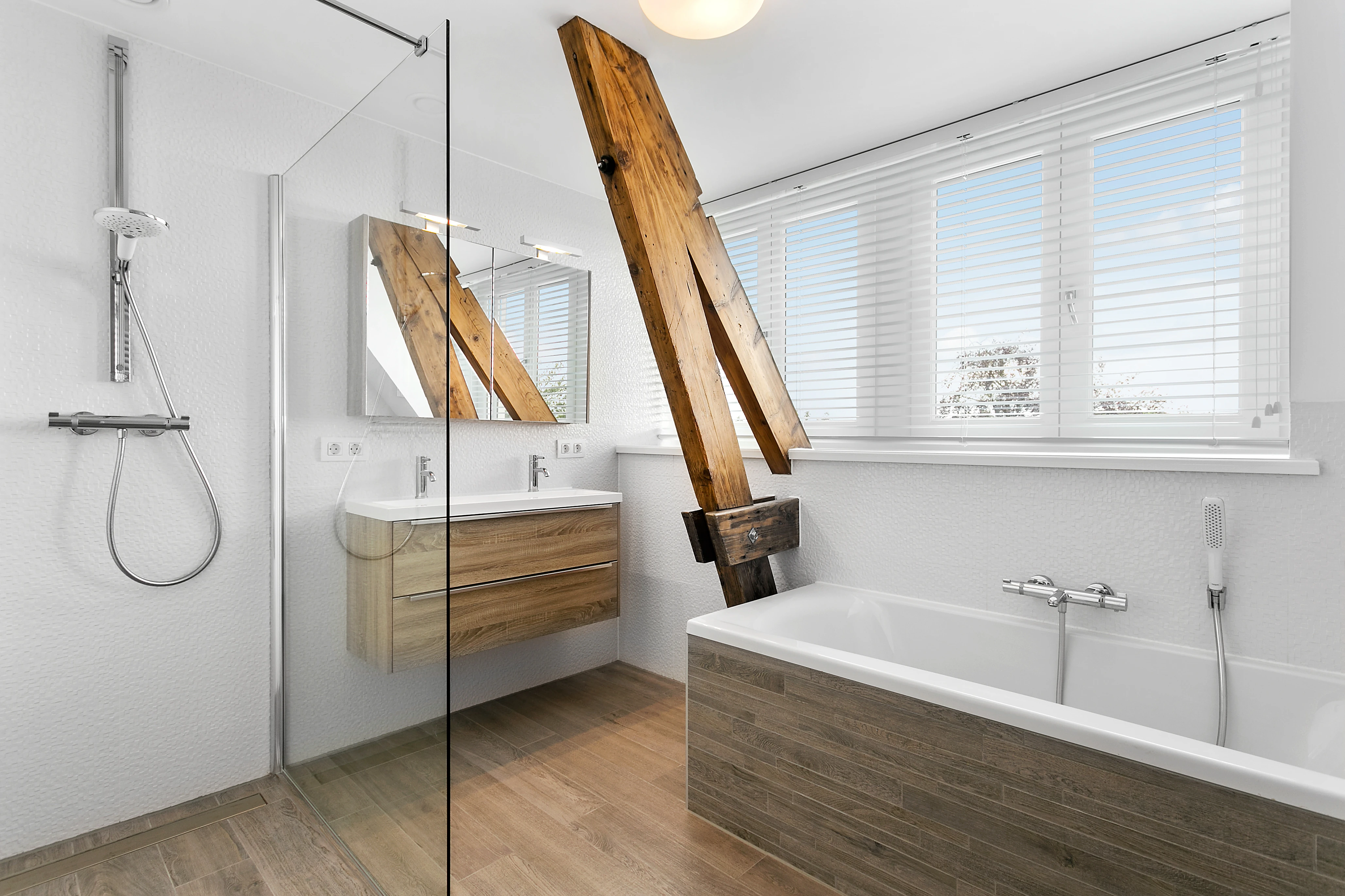 Badkamer op zolder met een vrijstaand ligbad onder een originele houten balk