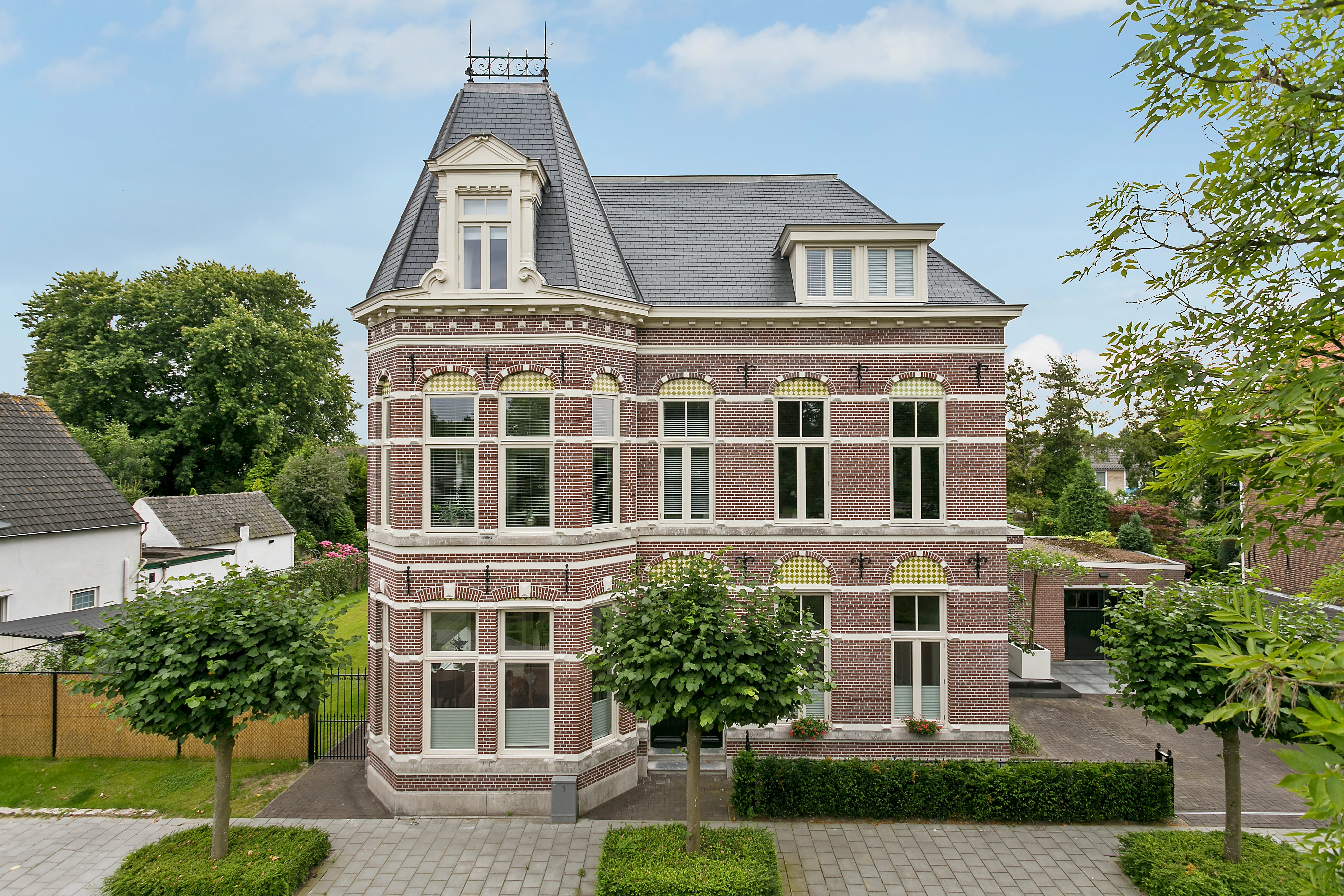 Voorgevel van het monumentale pand met torentje en erker, gezien vanaf de straat