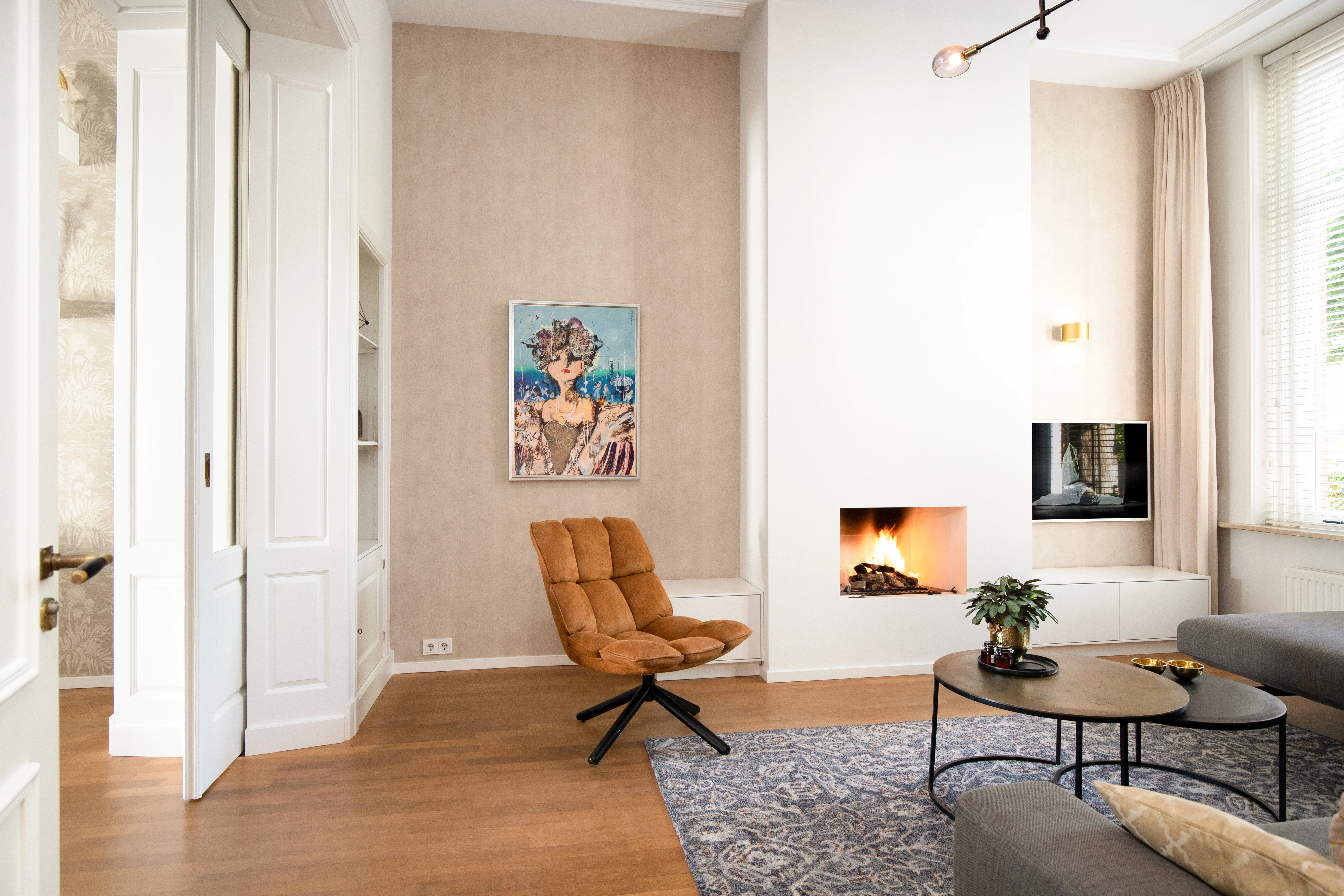 Woonkamer met een inbouwhaard, een portret aan de wand en een cognackleurige fauteuil