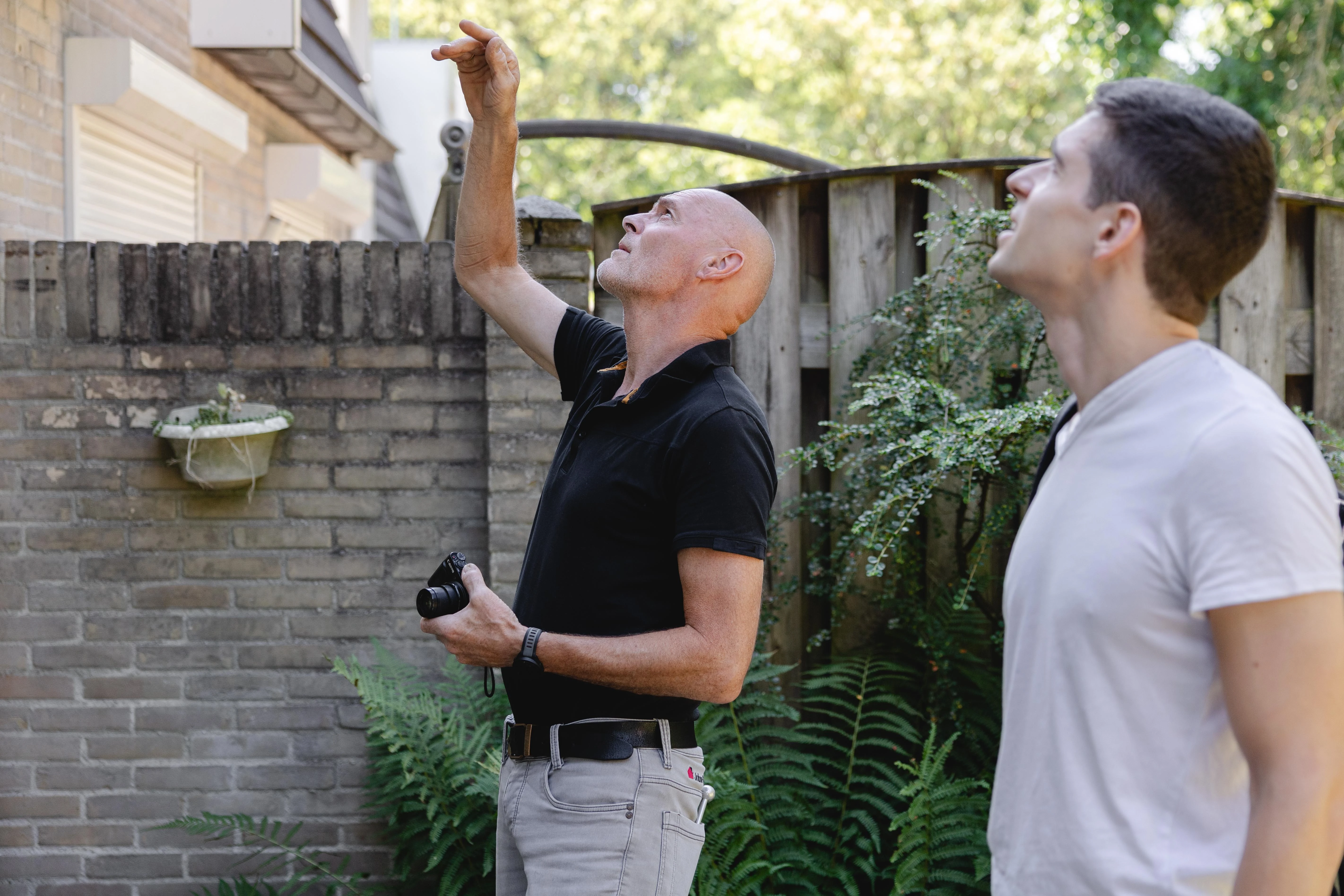 Energieprestatieadviseur wijst naar het dak terwijl hij dit met een bewoner bespreekt