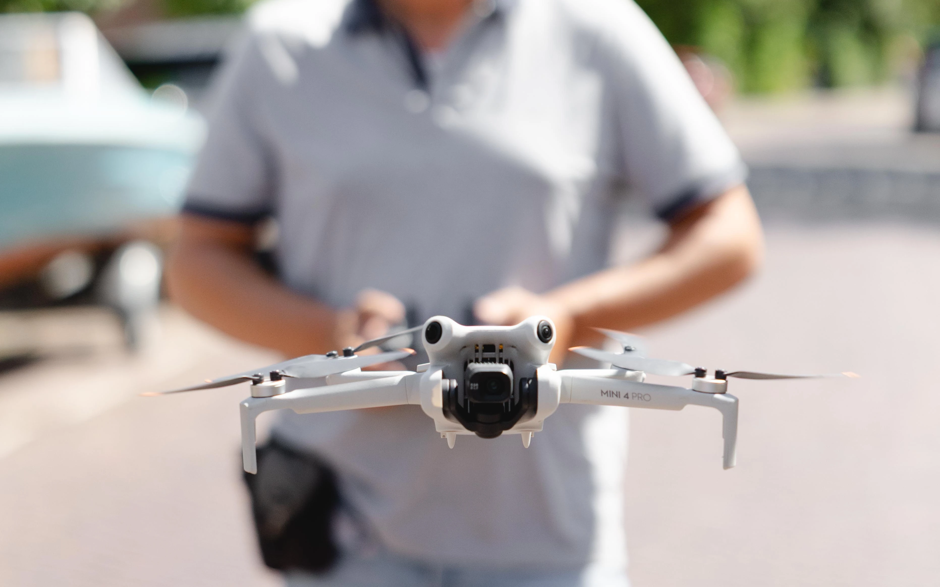 Dronepiloot met de afstandsbediening in handen, met de drone vlak voor zich in de lucht